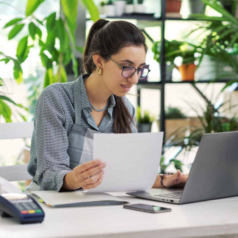 Femme fleuriste gérant sa comptabilité, devant son ordinateur portable dans sa boutique